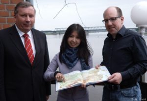 Assel Issajewa zeigt dem CDU-Bundestagsabgeordneten Norbert Brackmann (links) und dem Abgeordneten des Schleswig-Holsteinischen Landtags Markus Mathießen (rechts) Kasachstan.