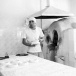 Kurbonali Nasriddinow ist dabei, sein Backwerk in den Tandyr-Ofen zu schieben. | Foto: Madinabonu Karimowa