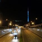 Blick auf den Kök-Töbe bei Nacht: Der Fernsehturm und die Achterbahn werden mit blauen, roten, grünen und gelben Lichtern angestrahlt. | Foto: Elke Kögler