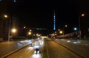 Blick auf den Kök-Töbe bei Nacht: Der Fernsehturm und die Achterbahn werden mit blauen, roten, grünen und gelben Lichtern angestrahlt. | Foto: Elke Kögler